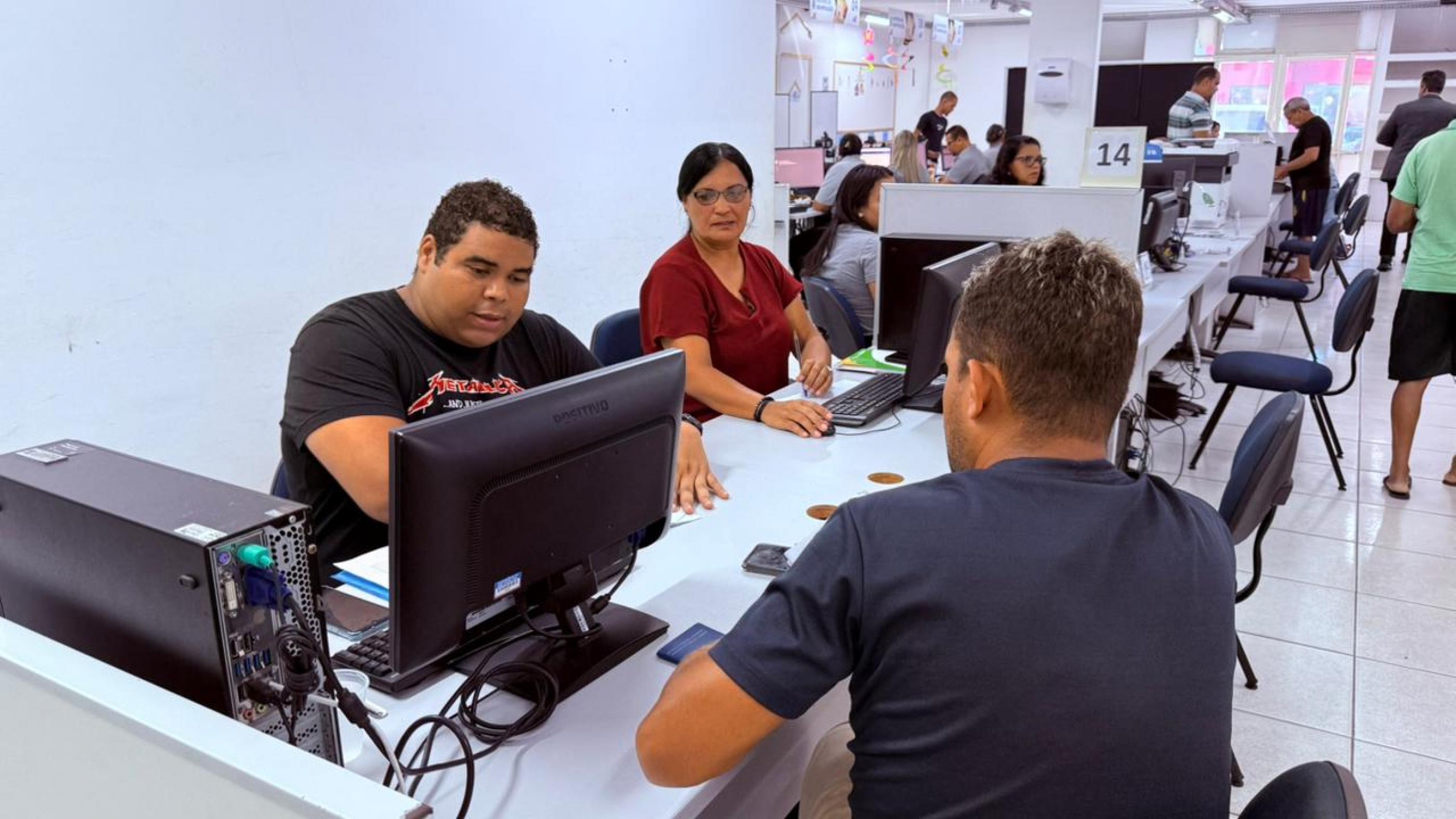Trabalhadora do Sine Alagoas atende uma pessoa em um balcão do serviço de emprego