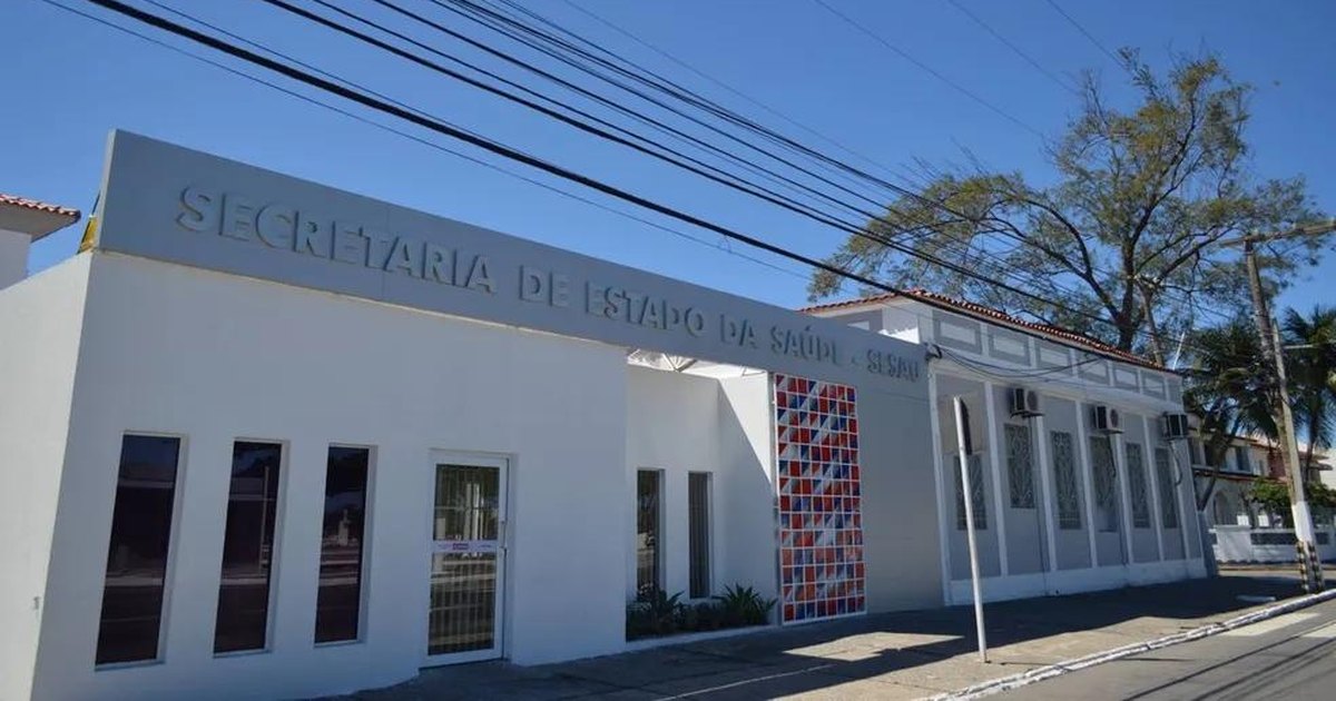 Fachada da Secretaria de Estado da Saúde de Alagoas, em Maceió, sob céu azul.