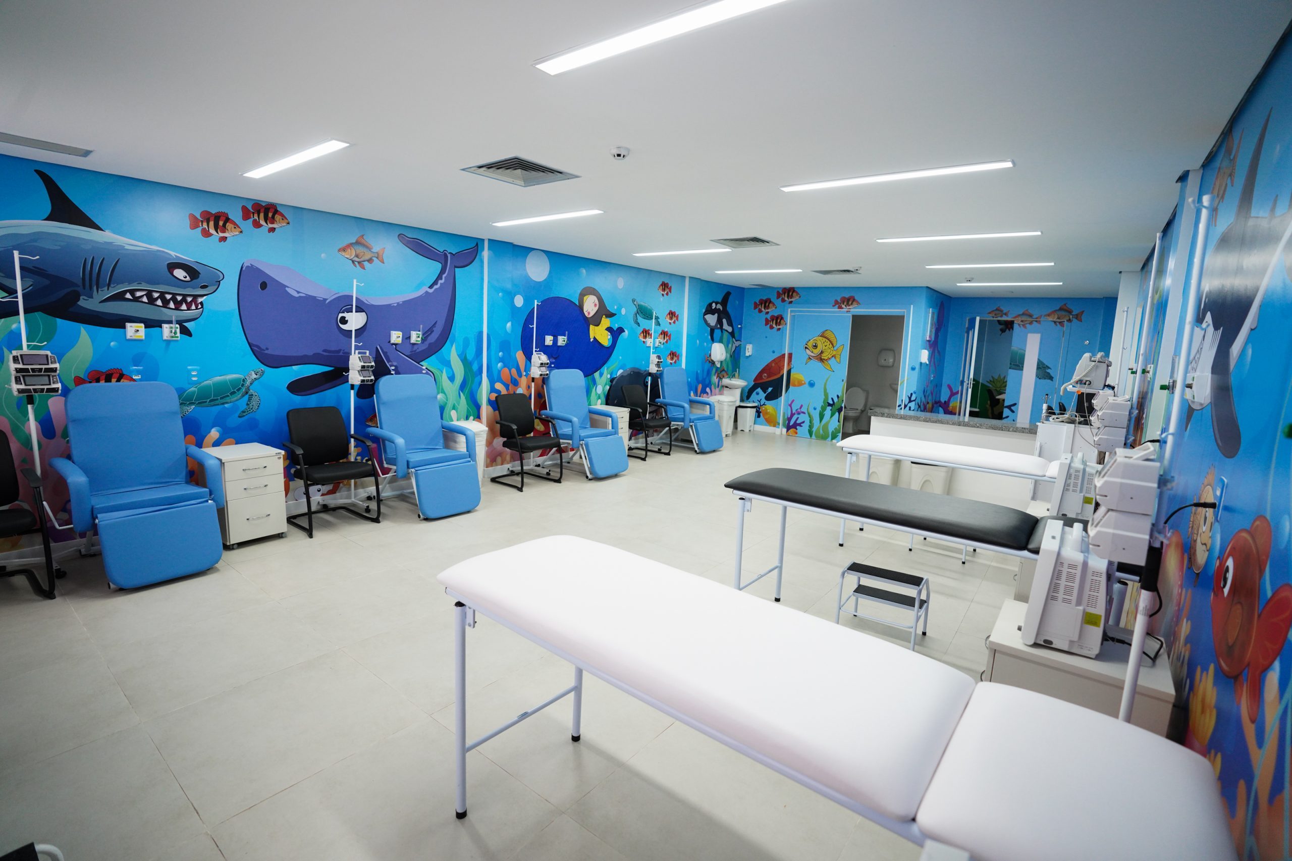 Sala de quimioterapia pediátrica do Hospital da Criança de Alagoas, com poltronas, macas e paredes decoradas com animais marinhos.
