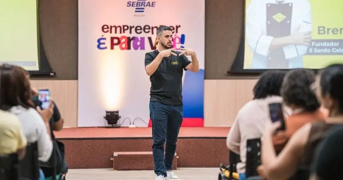Breno Oliveira se comunica em Libras durante palestra do encontro Empreender é Para Você, diante do público.