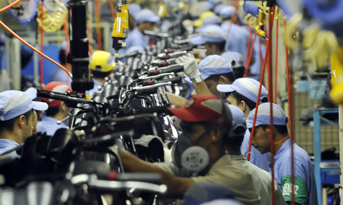 Trabalhadores montam motocicletas em linha de produção industrial
