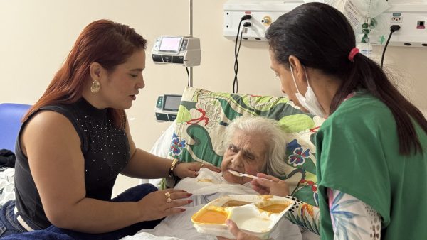 Liocrizia, de 96 anos, em cadeira de rodas ao lado de acompanhantes e profissional de saúde após receber alta hospitalar