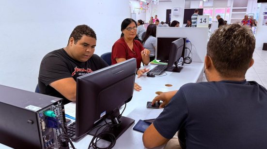 Trabalhadora atende uma pessoa em uma unidade do Sine Alagoas