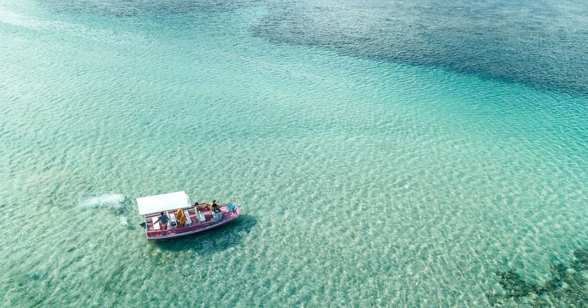 Embarcação navega sobre águas rasas e transparentes em Maragogi